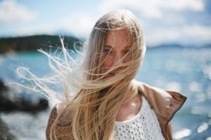 Blond girl with long hair looking at camera by the seaside